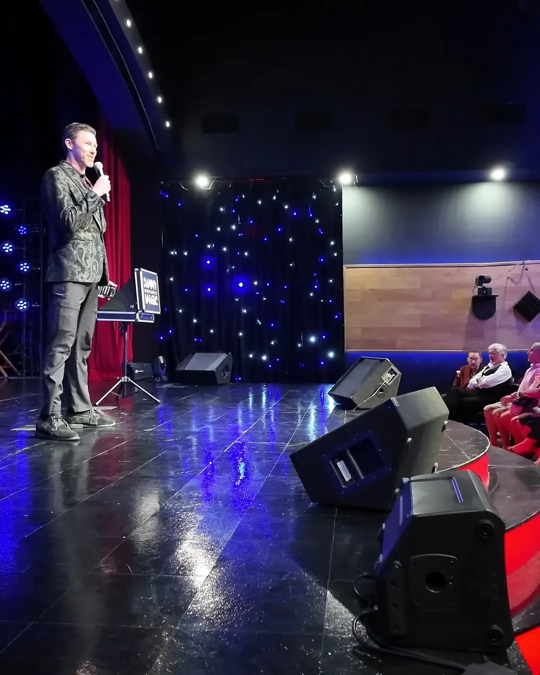 Stefan on stage with a microphone in front of a live audience