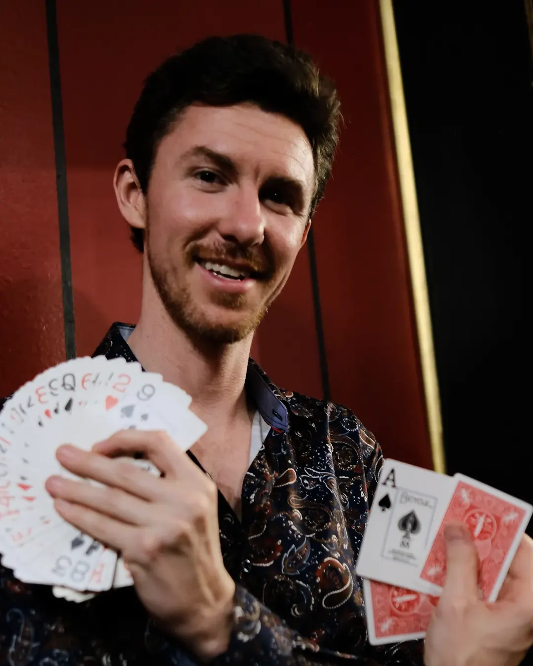 Stefan Oswald smiling and holding a fan of playing cards