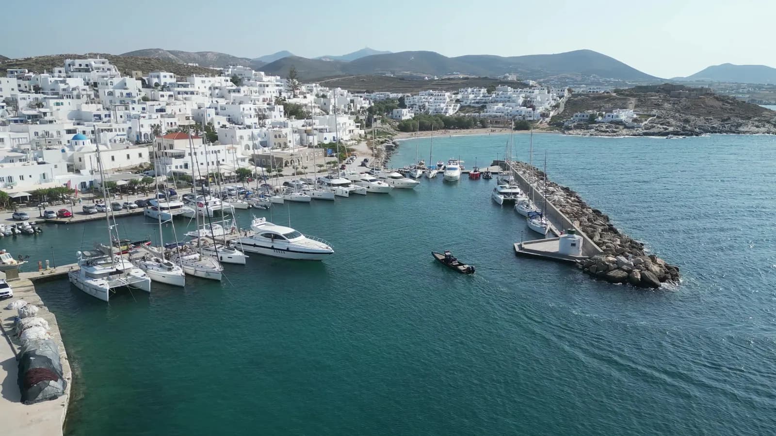 Aerial view of a marina full of sailboats and yachts in front of a white village